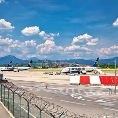 Samoloty Ryanair na lotnisku w Bergamo, gotowe do startu. Komunikacja miejska czeka na pasażerów.