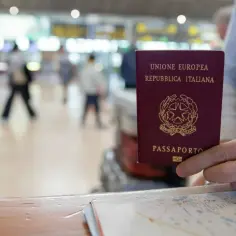 Włoski paszport w dłoni, na tle lotniska. Czy do Wiednia potrzebny jest paszport? Tak, jeśli nie jesteś obywatelem UE.