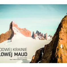 Dwaj alpiniści stoją na szczycie skalnej iglicy w lodowej krainie Królowej Maud. W tle mroźny krajobraz z górami i lodem.