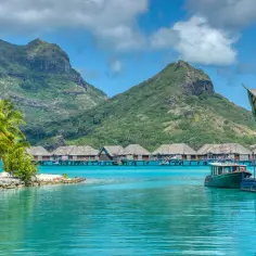 Bora Bora, gdzie jest? Rajskie widoki: palmy, turkusowa woda, góry i domki na wodzie.