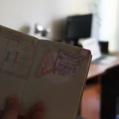 Otwarty paszport z pieczątkami z Meksyku i Malezji. W tle biurko z laptopem. Ile cyfr ma paszport?