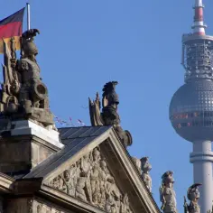 Niemiecka flaga powiewa nad rzeźbami na dachu, w tle widać wieżę telewizyjną. Berlin zielona strefa.