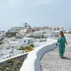 Kobieta spaceruje po urokliwej ścieżce na Santorini. Aktualna sytuacja w Grecji dla turystów jest idealna na podziwianie widoków.