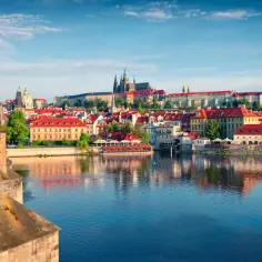 Widok na Pragę z mostu, z zamkiem na wzgórzu i rzeką Wełtawą. Ceny w Pradze mogą być różne, ale widoki są bezcenne.