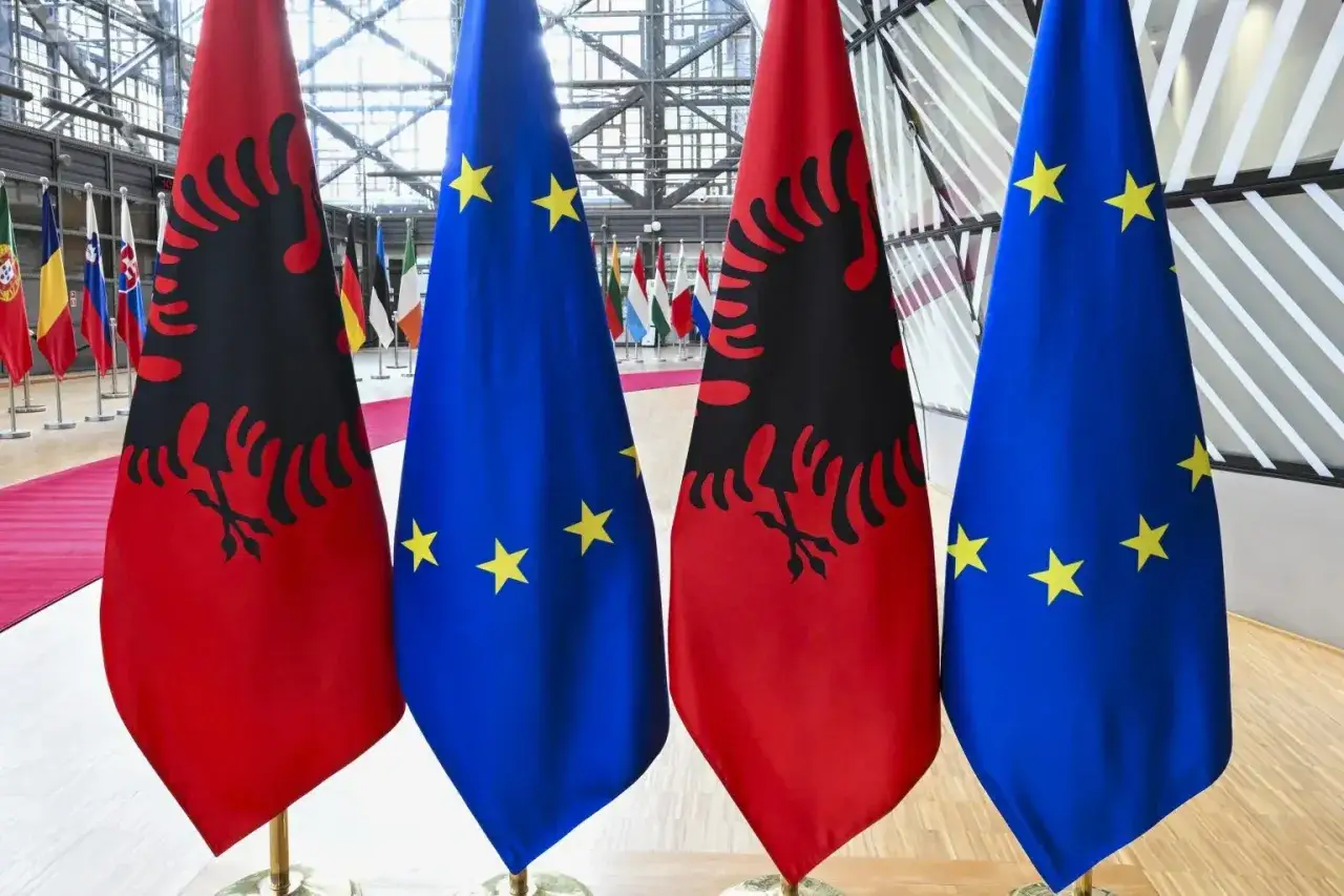 Flagi Albanii i Unii Europejskiej stoją obok siebie, sugerując dyskusję o tym, czy Albania jest w Unii Europejskiej.