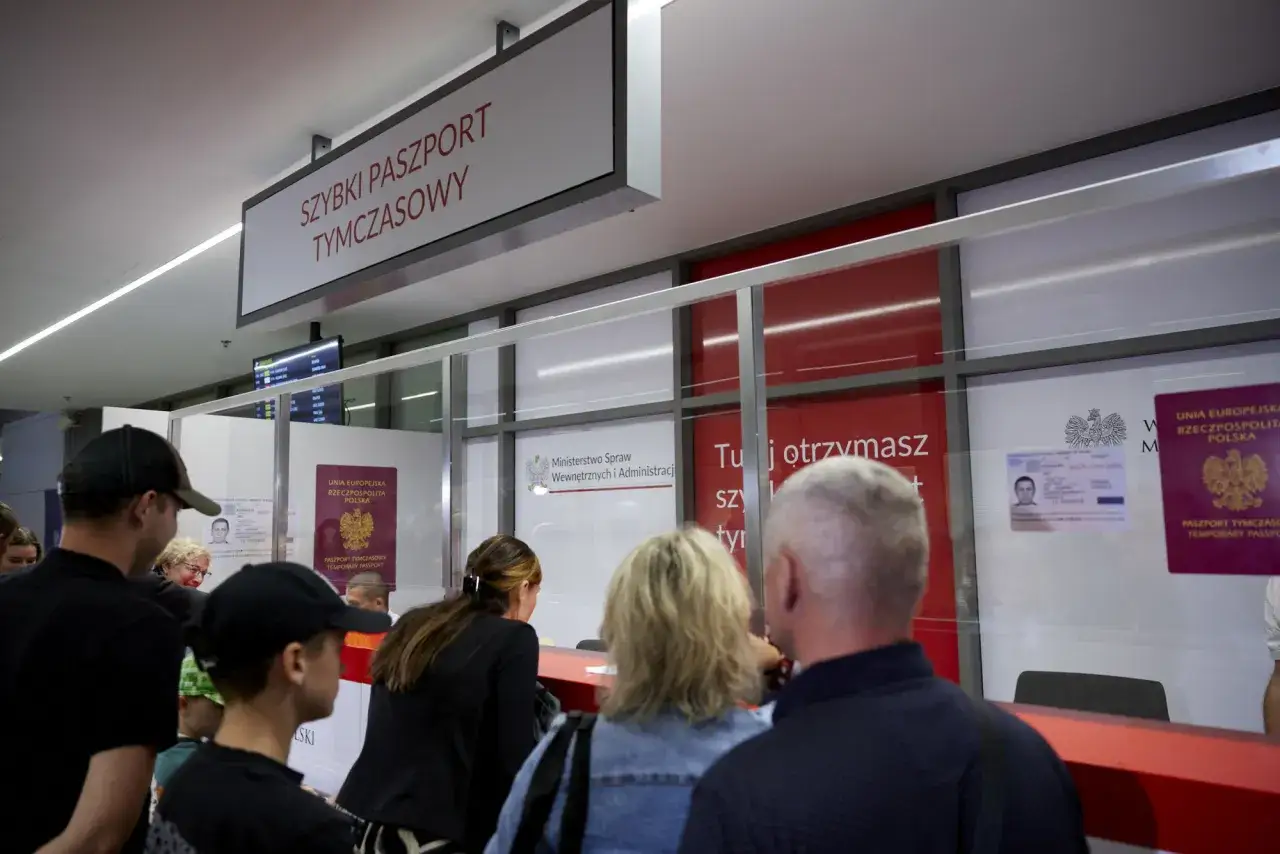 Kolejka do okienka, gdzie wyrabia się paszport tymczasowy. W tle widać tablicę informacyjną i dokumenty.