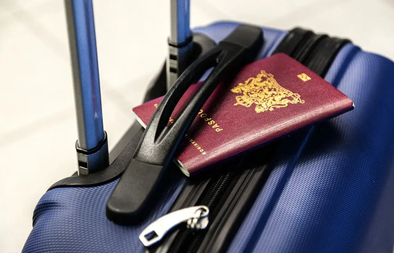 Dwa paszporty leżą na niebieskiej walizce, gotowe do podróży. Kto ma zniżkę na paszport, ten może liczyć na tańsze bilety.