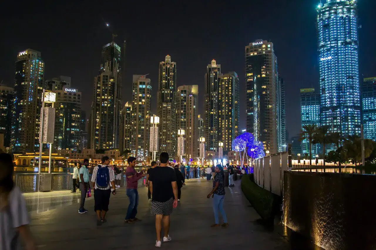 Nocny spacer po Dubaju, wśród lśniących wieżowców. Czy do Dubaju potrzebna jest wiza? Tłum ludzi cieszy się wieczorem.