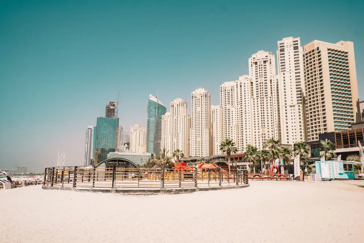 Plaża w Dubaju z wieżowcami w tle. Zastanawiasz się, czy do Dubaju potrzebna jest wiza? Sprawdź przed podróżą!