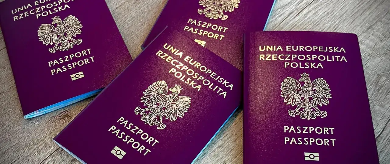 Kilka polskich paszportów leży na drewnianym blacie. Czas na wymianę, kiedy paszport traci ważność.