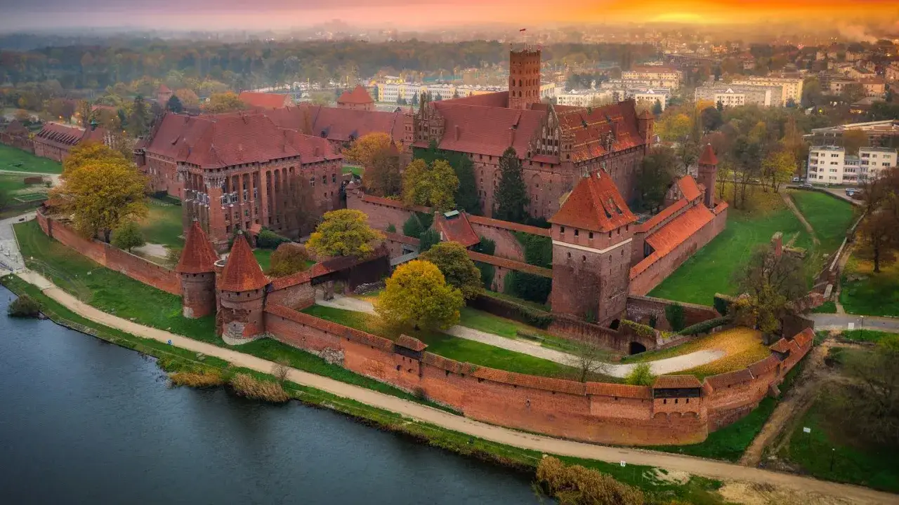 Zamek w Malborku, największa ceglana twierdza świata, zachwyca jesienią. Ciekawostki o jego historii i architekturze przyciągają turystów.