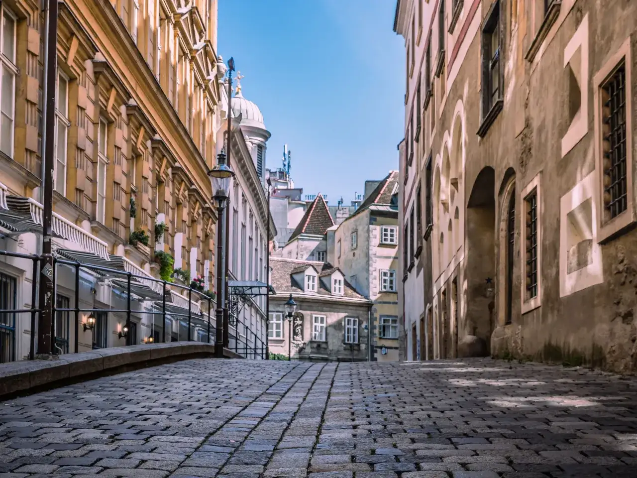 Urokliwa, brukowana uliczka w Wiedniu, gdzie historyczna architektura i niebo tworzą malowniczy widok. Ceny w Wiedniu mogą być różne, ale widoki są bezcenne.