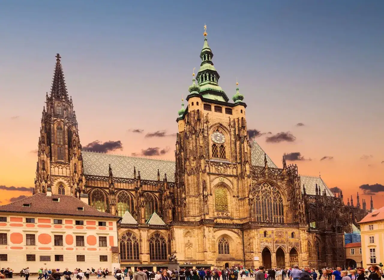 Majestatyczna katedra na wzgórzu zamkowym w Pradze, z tłumem turystów na placu przed nią.