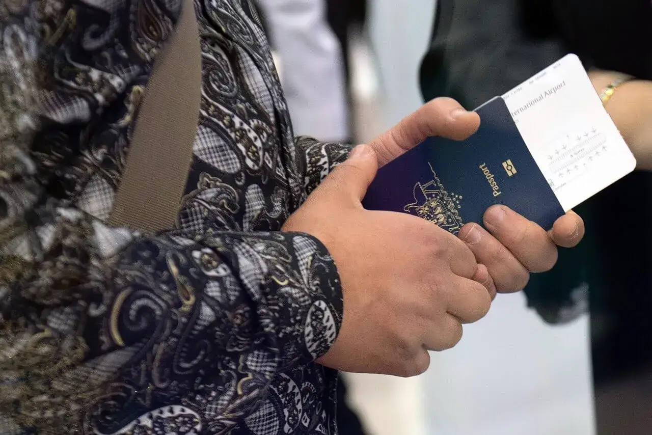 Ręce trzymają paszport i kartę pokładową. Czy na Arubę potrzebny jest paszport? Tak, do podróży na Arubę wymagany jest paszport.