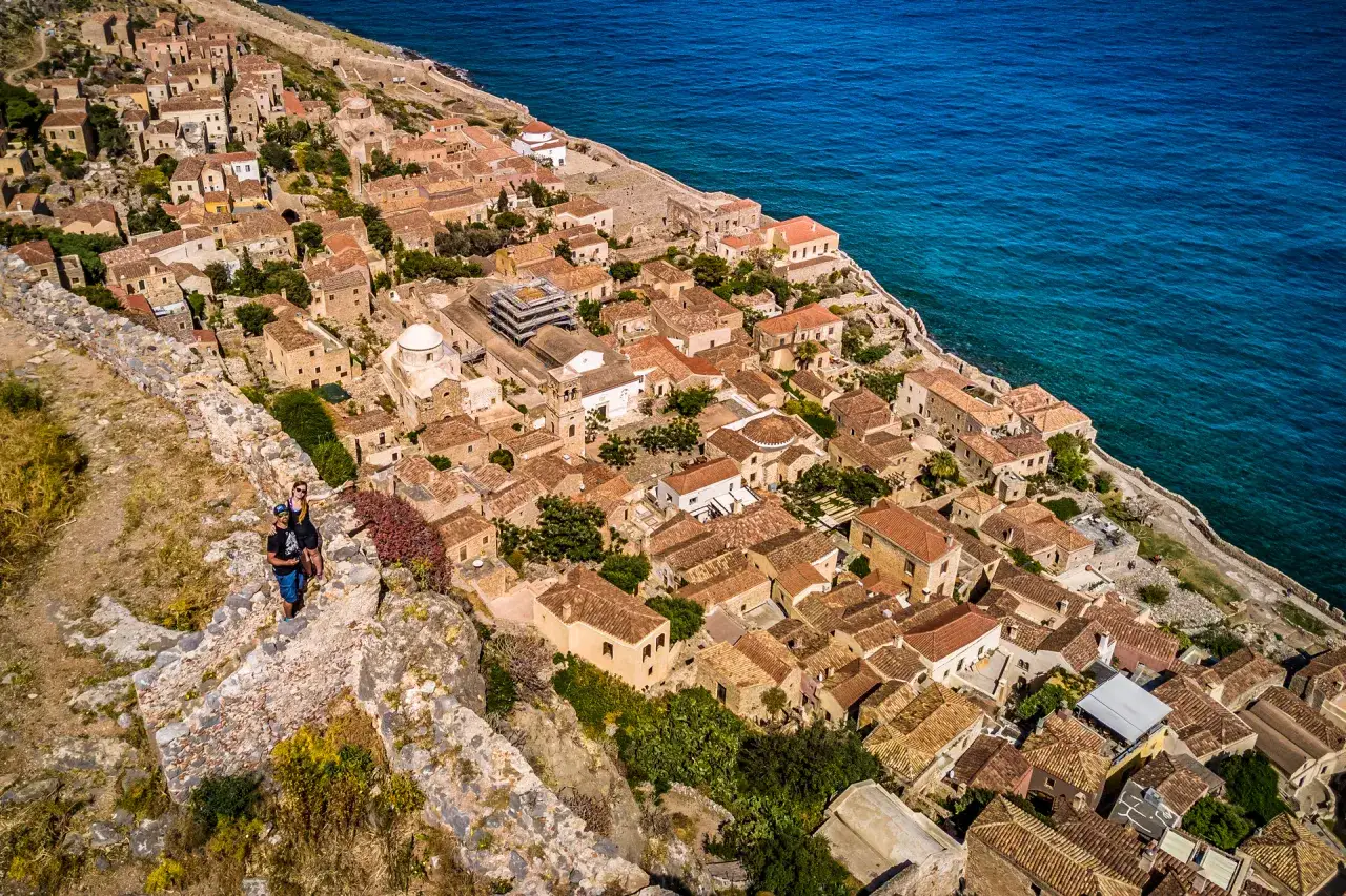 Widok na zabytkowe miasta na Peloponezie, z dwoma turystami na murze obronnym.