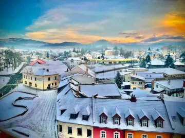 Zimowy krajobraz małego miasteczka w Czechach, idealny na weekend blisko granicy. Dachy pokryte śniegiem, góry w oddali.