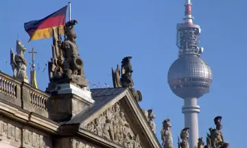 Niemiecka flaga powiewa nad rzeźbami na dachu, w tle widać wieżę telewizyjną. Berlin zielona strefa.