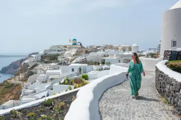 Kobieta spaceruje po urokliwej ścieżce na Santorini. Aktualna sytuacja w Grecji dla turystów jest idealna na podziwianie widoków.