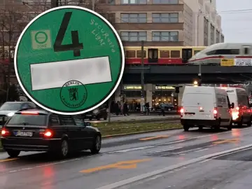 Wjazd do Berlina samochodem. Zielona naklejka Umweltzone z numerem 4 na szybie auta. W tle pociąg i budynki.
