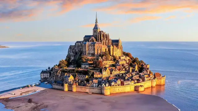 Mont Saint-Michel, jedno z najpiękniejszych miejsc we Francji, majestatycznie wznosi się z morza o zachodzie słońca.