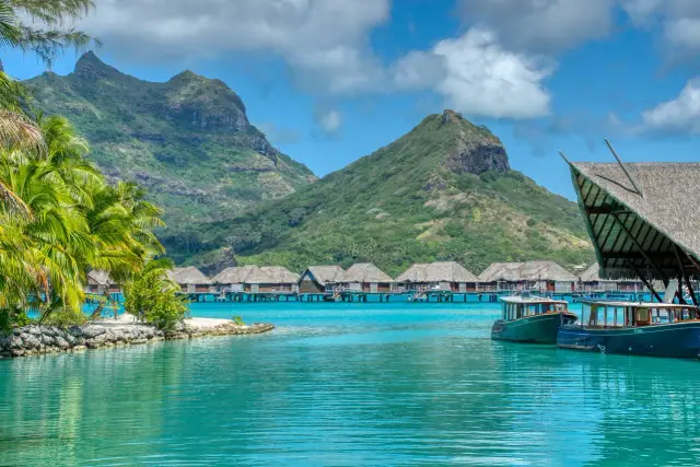 Bora Bora, gdzie jest? Rajskie widoki: palmy, turkusowa woda, góry i domki na wodzie.