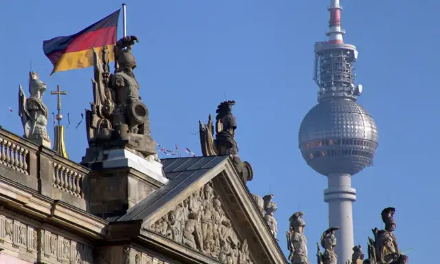 Niemiecka flaga powiewa nad rzeźbami na dachu, w tle widać wieżę telewizyjną. Berlin zielona strefa.